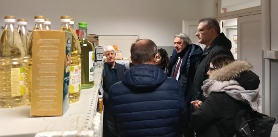 Un gruppo di persone tra gli scaffali del Social Market: tra loro il sindaco facente funzioni Piciocchi e il presidente Uremassi