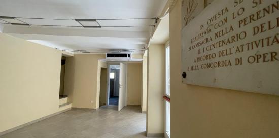 Foto del corridoio interno di vico Vegetti, in primo piano una porzione della targa a ricordo della SOMS Lavoratori del Legno