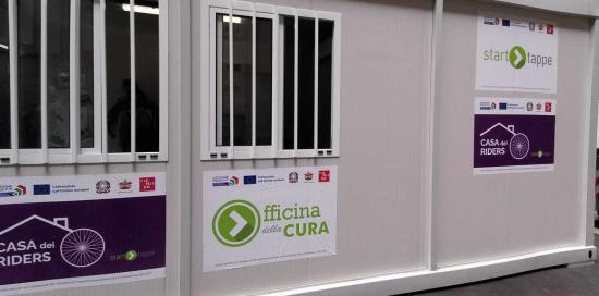 l'esterno del prefabbricato con le insegne casa dei riders e officina di cura