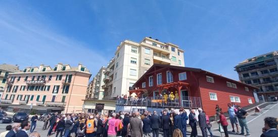 folla all'inaugurazione davanti alla casa in legno rosso 