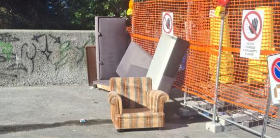 Un divanetto abbandonato in prossimità di un'area di cantiere Un divanetto abbandonato in prossimità di un'area di cantiere insieme ad altri rifiuti ingombranti