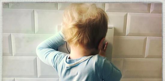 Foto di bambino piccolo poggiato a un muro mentre gioca Foto di bambino piccolo poggiato a un muro mentre gioca
