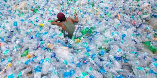 persona che nuota in un mare di bottiglie di plastica