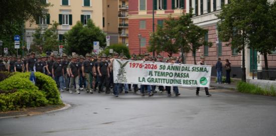 Alpini sfilano tenendo lo striscione dedicato ai 50 anni dal sisma del Friuli: "Il tempo passa, la gratitudine resta"