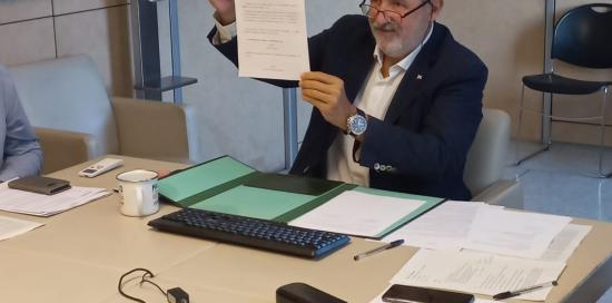 Il sindaco Bucci con in mano la copia sottoscritta del patto di collaborazione con Lima firmato da remoto
