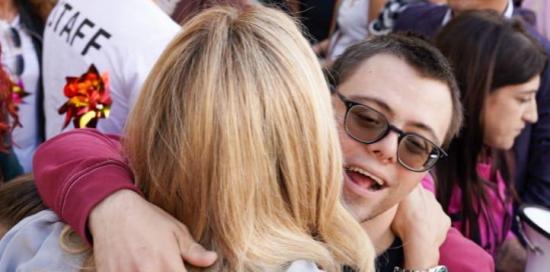 La sindaca Salis, fotografata di spalle, abbraccia un ragazzo con la sindrome di Down