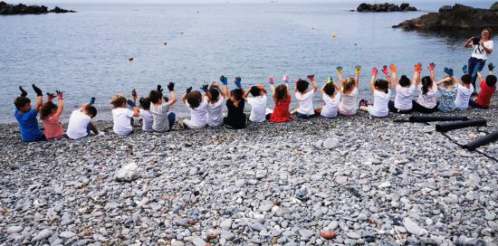 Bimbi sulla spiaggia a braccia alzate in segno di vittoria dopo una raccolta di piccoli rifiuti - foto di repertorio