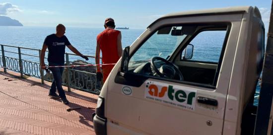 Due operai Aster al lavoro sulla passeggiata di Nervi: in primo piano il porter con il logo dell'azienda