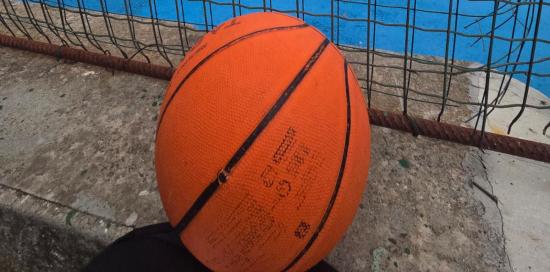 Un pallone da basket accanto alla recinzione del nuovo campetto