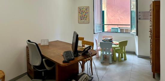 Uno dei locali della nuova sede ATS: scrivania con computer, tavolino con seggioline per bimbi