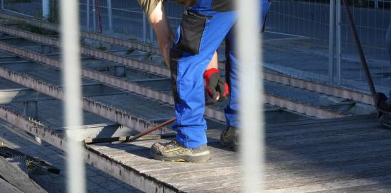 Un addetto impegnato nello smontaggio di un asse di legno della pedana