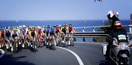 Ciclisti sull'Aurelia in una vecchia edizione della Milano-Sanremo con il mare sullo sfondo