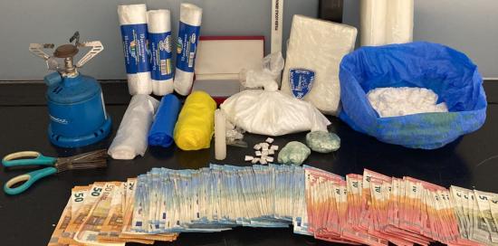 banconote, stupefacenti e altri oggetti sequestrati esposti su di un tavolo