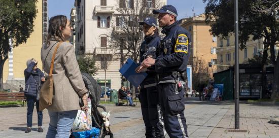 agenti e signora di spalle con bambino nel passeggino