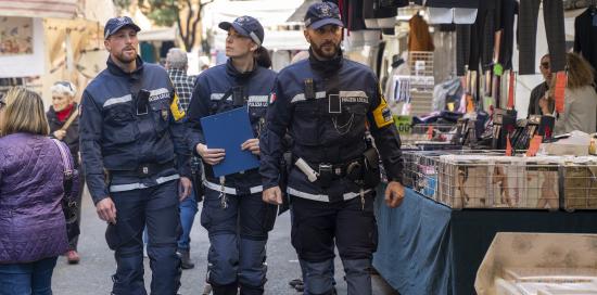 tre agenti camminano tra banchi di mercato rionale
