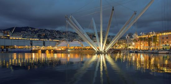 Foto del Porto Antico scattata dal mare: spicca il contrasto tra il grigio del cielo e il Porto Antico illuminato