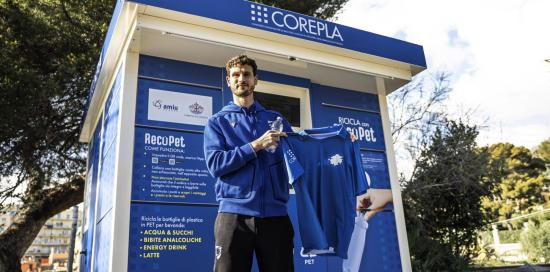 Il giocatore della Samp Oliver Abildsgaard davanti ad un ecocompattatore, con in mano la maglietta eco-friendly blucerchiata