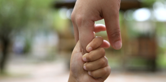 Due mani, una più grande e l'altra più piccola, che si intrecciano Due mani, una più grande e l'altra più piccola, che si intrecciano