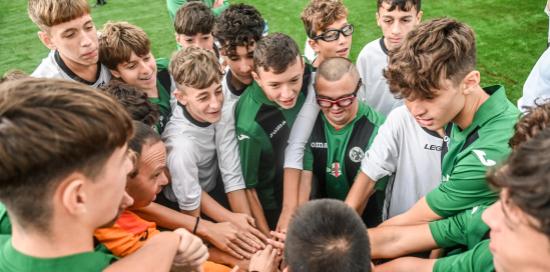 Un gruppo di bimbi su un campo di calcio, tra loro un coetaneo con la sindrome di Down