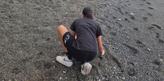 Una ragazza intenta a raccogliere mozziconi sulla spiaggia
