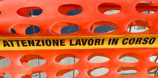 scritta "attenzione lavori in corso" su rete di cantiere color arancio