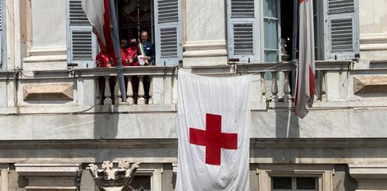 la bandiera della Croce rossa esposta sulla facciata di palazzo Tursi