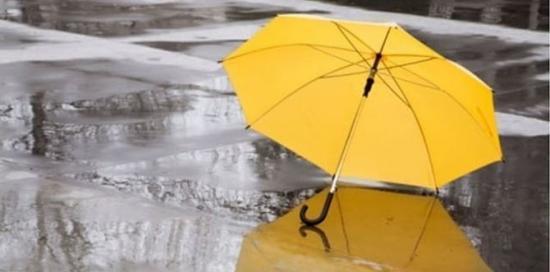 Ombrello giallo appoggiato sulla strada mentre piove