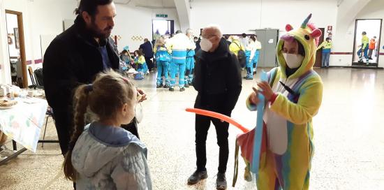 l'animatrice in costume da orsetto giallo porge un palloncino a una bimba di spalle