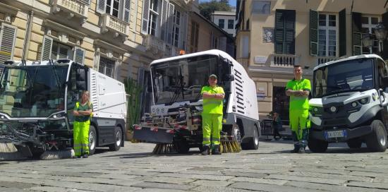 Panoramica su tre nuovi mezzi elettrici con davanti tre addetti di Amiu in posa