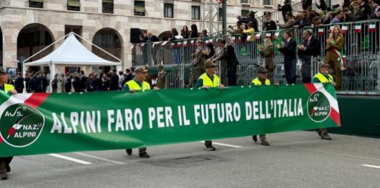 Alpini portano lo striscione con scritta bianca su sfondo verde "Alpini faro per il futuro dell'Italia"