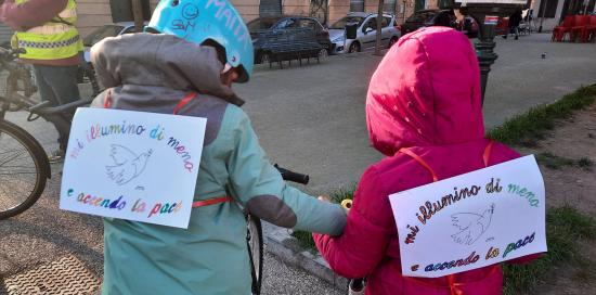 due bambini di spalle con cartelli M'illumino di meno e 