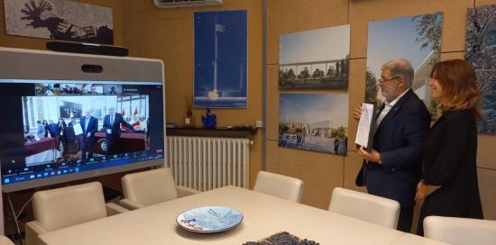 Il sindaco Bucci con in mano la copia sottoscritta del patto di collaborazione con Lima firmato da remoto