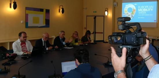 Un cameraman al lavoro durante la conferenza stampa mentre riprende i vari relatori raccolti attorno al tavolo