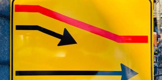 Un cartello giallo &quot;di cantiere&quot; che indica un restringimento di carreggiata