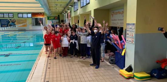 giovani sportivi e istruttori a bordo piscine esultano a braccia alzate 