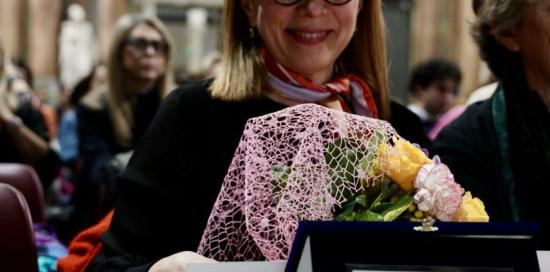 Raffaella Romagnolo sorridente con targa e fiori dopo essere stata proclamata vincitrice