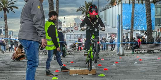 bambino supera ostacolo in bici al porto antico sotto la guida di un istruttore