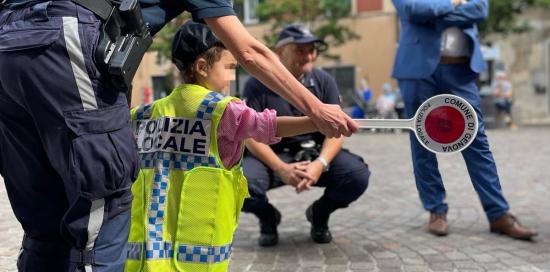 agente di polizia guida un bimbo nell'uso della paletta