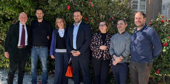 Foto nel cortile di Tursi con relatori e relatrici della conferenza stampa: sullo sfondo una siepe di camelie