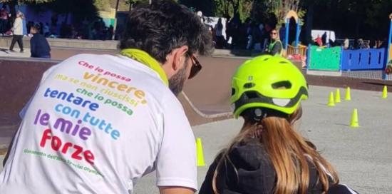 Un adulto, fotografato di spalle, aiuta una bambina ad andare in bicicletta Un adulto, fotografato di spalle, aiuta una bambina ad andare in bicicletta