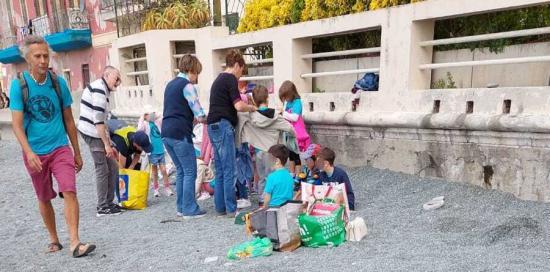 Bimbe e bimbi sullo sfondo, in primo piani i sacchi per la raccolta differenziata dei rifiuti raccolti