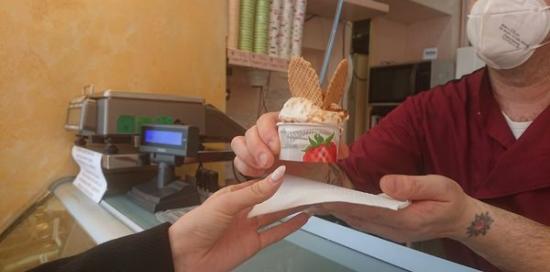 particolare del gesto del gelataio che porge un gelato