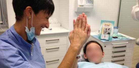 Una dentista volontaria di Arkè "dà il 5" a una bimbaa che ha appena ricevuto assistenza dentistica
