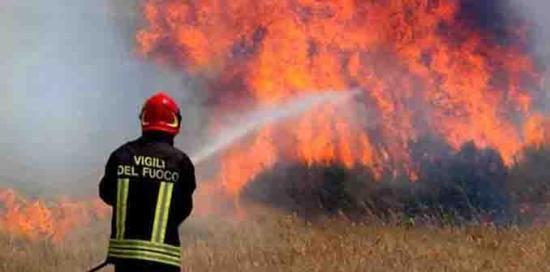 Un Vigile del Fuoco intento a spegnere un fuoco con una manichetta antincendio Un Vigile del Fuoco intento a spegnere un fuoco con una manichetta antincendio
