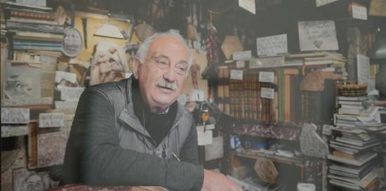 Un anziano artigiano fotografato all'interno della sua bottega, attorniato dalle sue produzioni