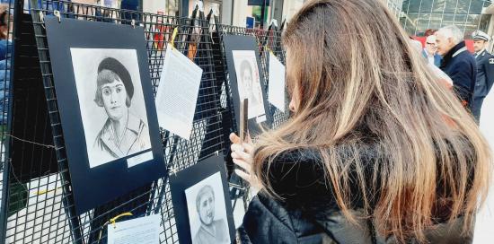 Una visitatrice della mostra fotografa uno dei 22 ritratti delle Madri Costituenti appesi all'ex mercato di corso Sardegna