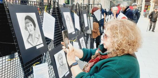 Una visitatrice della mostra fotografa uno dei 22 ritratti delle Madri Costituenti appesi all'ex mercato di corso Sardegna