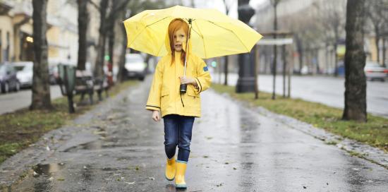 Bambina con ombrello, impermeabile e stivali gialli