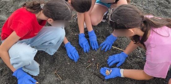 Un gruppo di ragazze intente a raccogliere mozziconi sulla spiaggia