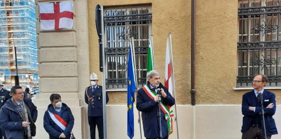 il sindaco parla davanti alla targa ancora coperta dalla bandiera di Genova
